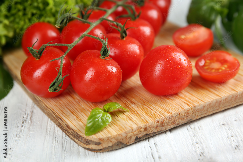 Cherry tomatoes with basil on wooden table close up Cherry tomatoes with basil on wooden table close up