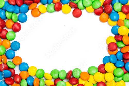 Frame of colorful chocolate candy on white background with space