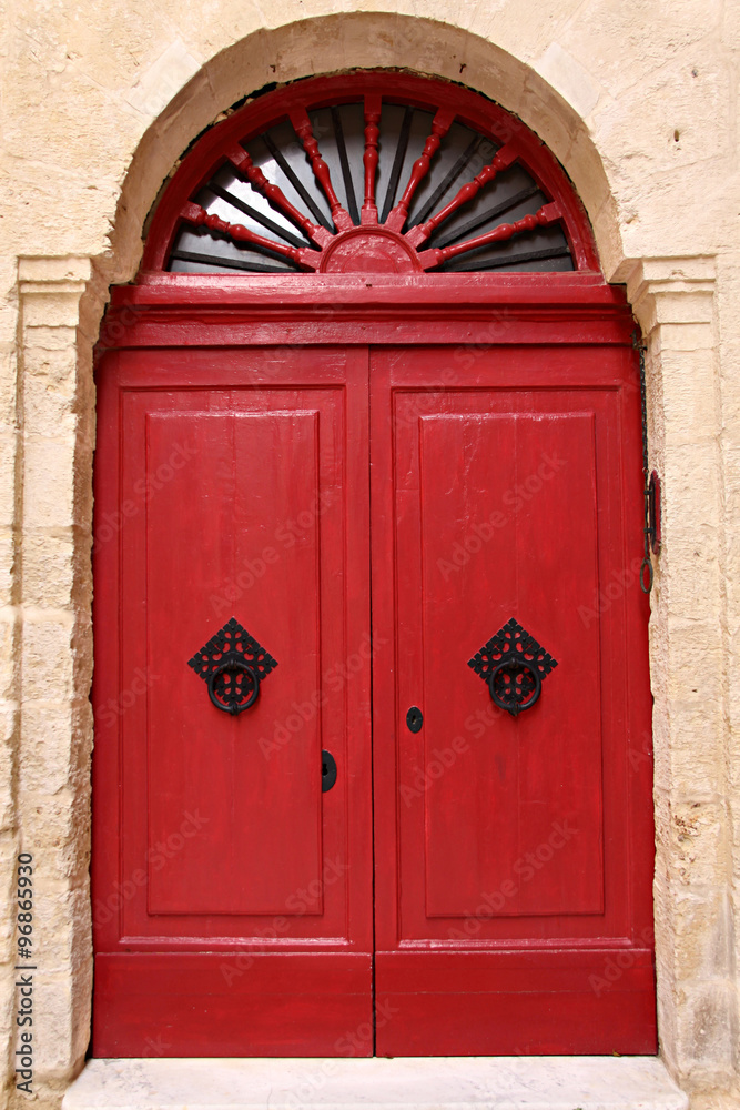 Puerta de madera roja con tiradores negros.