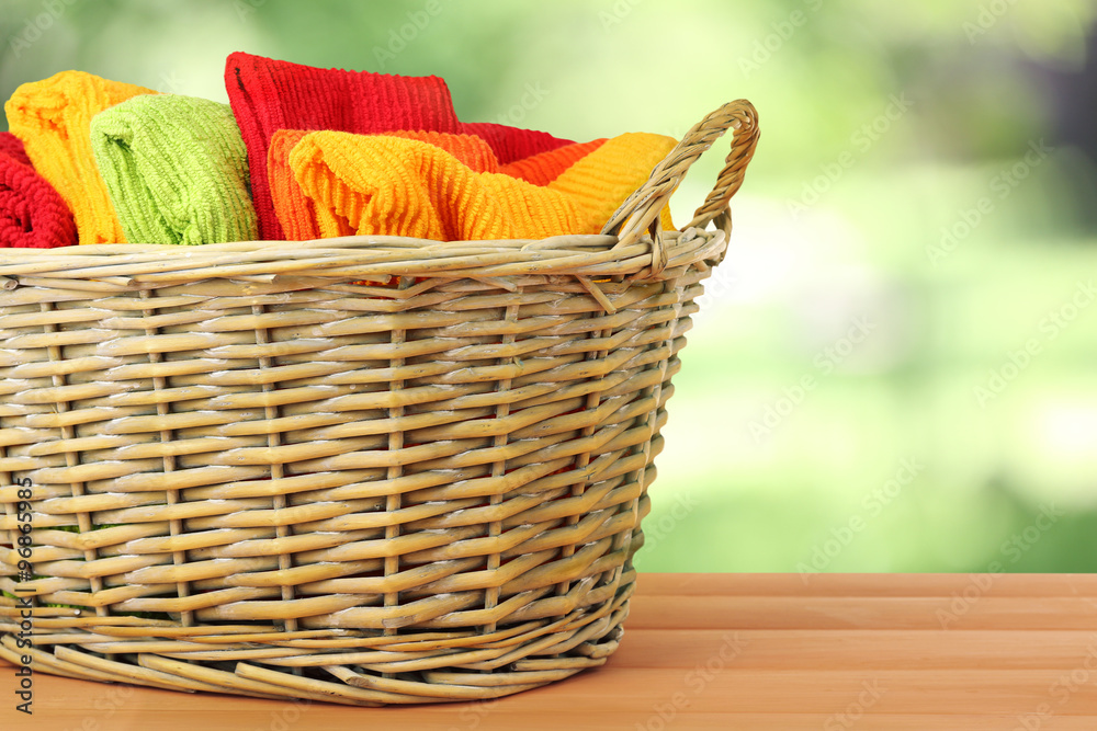 Colorful towels in basket on bright background