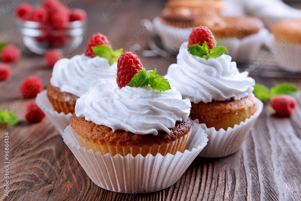Delicious cupcakes with berries and fresh mint on wooden table close up Delicious cupcakes with berries and fresh mint on wooden table close up