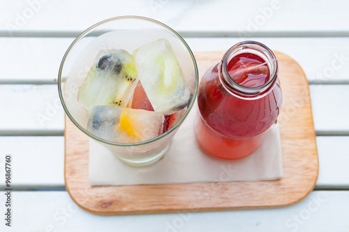 Self pouring ice tea serve with ice cube with fruits frozen insi photo