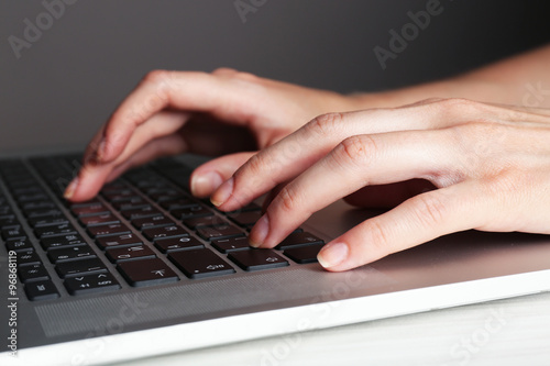 Female hands typing on laptop keyboard, closeup