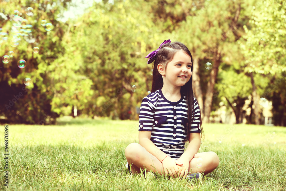 Happy little girl with bubbles on the green grass in the park Happy little girl with bubbles on the green grass in the park