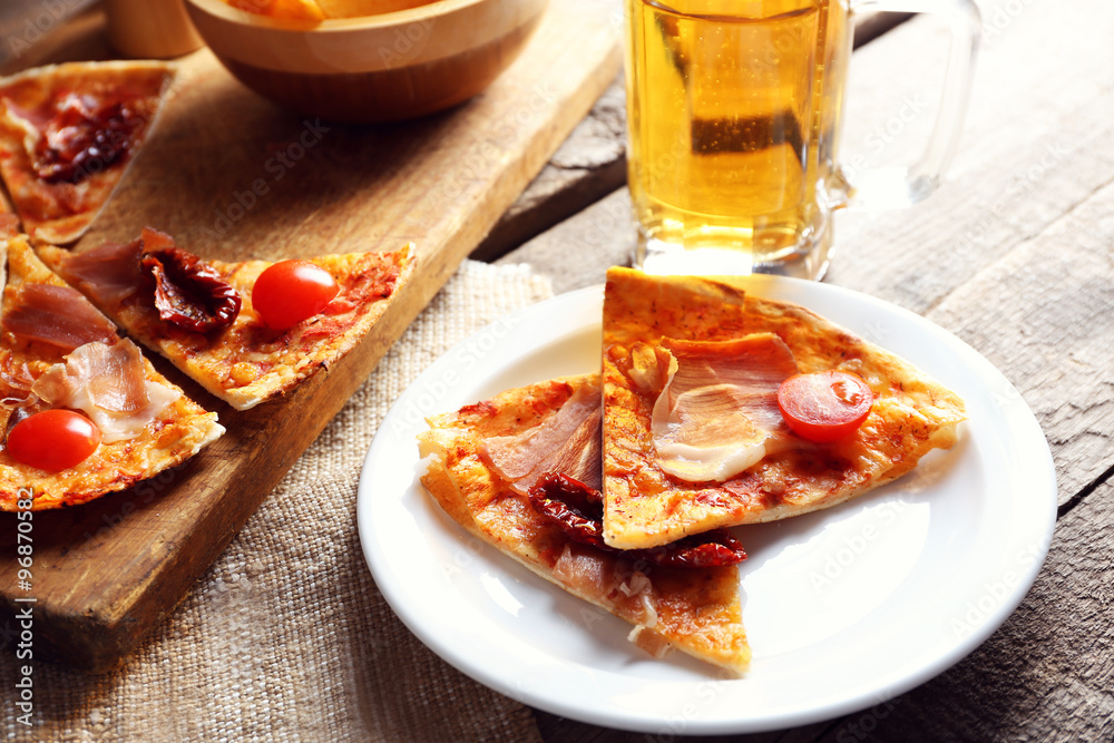 Sliced pizza served with beer on wooden table Sliced pizza served with beer on wooden table