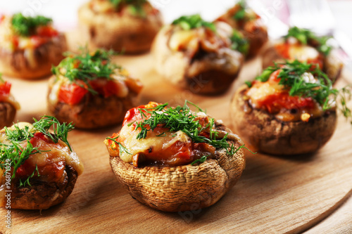 A wooden tablet with stuffed mushrooms on the table, close-up