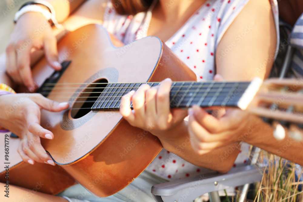 Fototapeta premium Attractive couple playing guitar, outdoors, close up