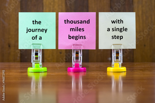 Картината върху платно Word quotes of THE JOURNEY OF A THOUSAND MILES BEGINS WITH A SINGLE STEP on colorful sticky papers against wooden textured background