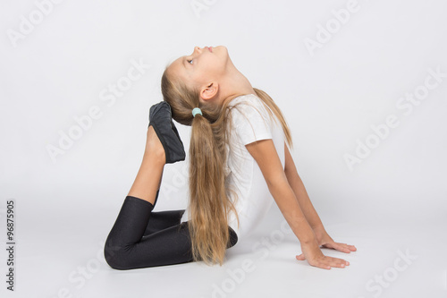 Girl gymnast performs exercises toes touching head
