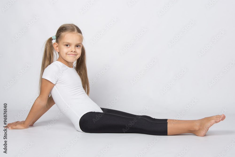 Girl gymnast sitting on the floor with legs stretched and leaned back on his hands Girl gymnast sitting on the floor with legs stretched and leaned back on his hands
