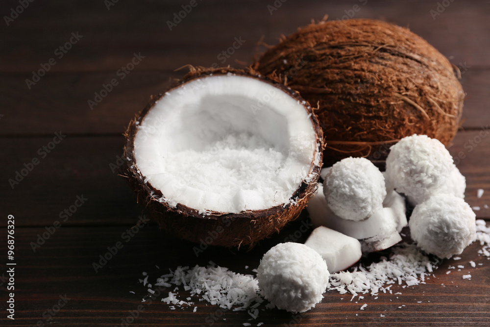 Candies in coconut flakes and fresh coconut on dark wooden background Candies in coconut flakes and fresh coconut on dark wooden background