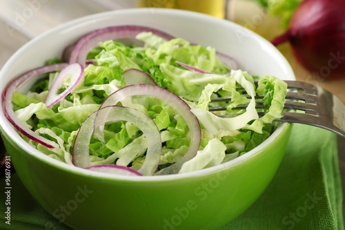 Savoy cabbage and onion salad served in bowl on wooden table