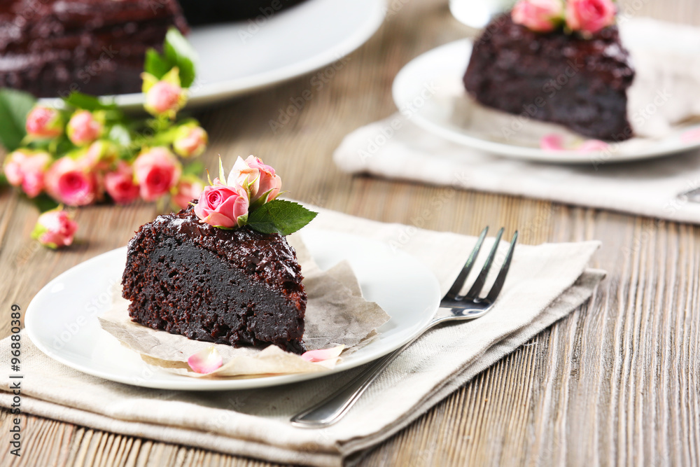 Piece of chocolate cake decorated with flowers on brown wooden table Piece of chocolate cake decorated with flowers on brown wooden table
