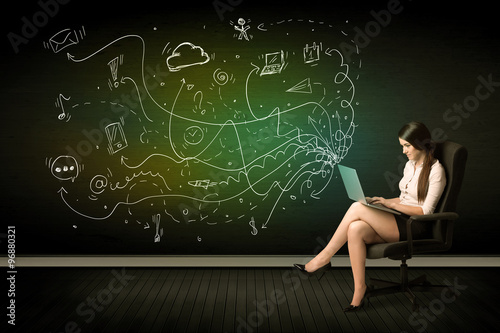 Businesswoman sitting in chair holding laptop with media icons
