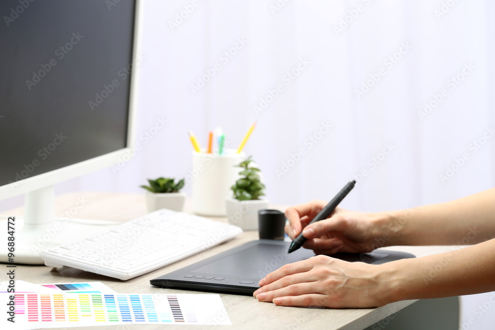 Fototapeta premium Female hand drawing on the graphic tablet in the office, close-up
