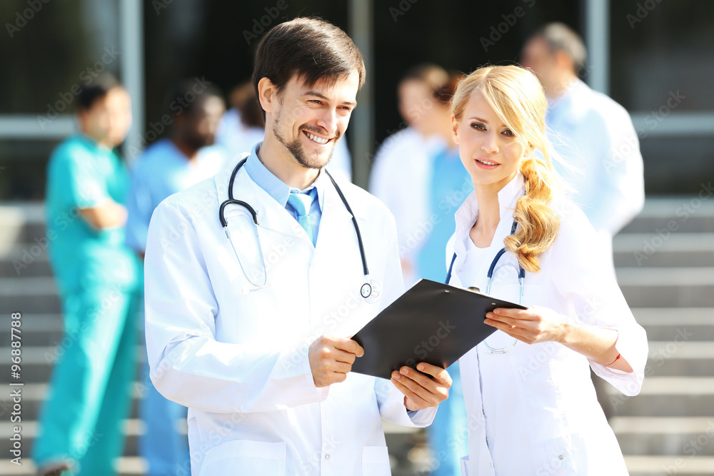 Medical concept - two doctors with stethoscopes and prescription clipboard Medical concept - two doctors with stethoscopes and prescription clipboard