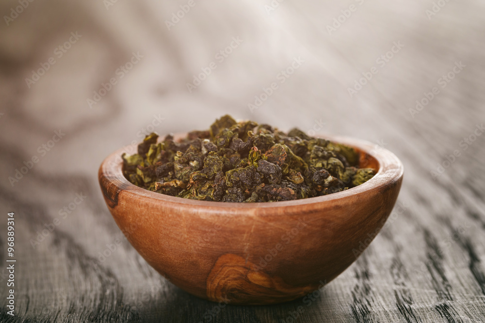oolong green tea in wood bowl on oak table oolong green tea in wood bowl on oak table