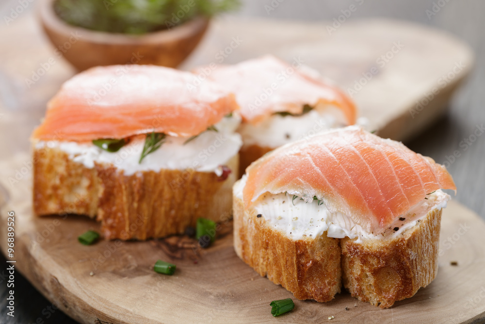 baguette slices with soft cheese and salmon on wood table baguette slices with soft cheese and salmon on wood table
