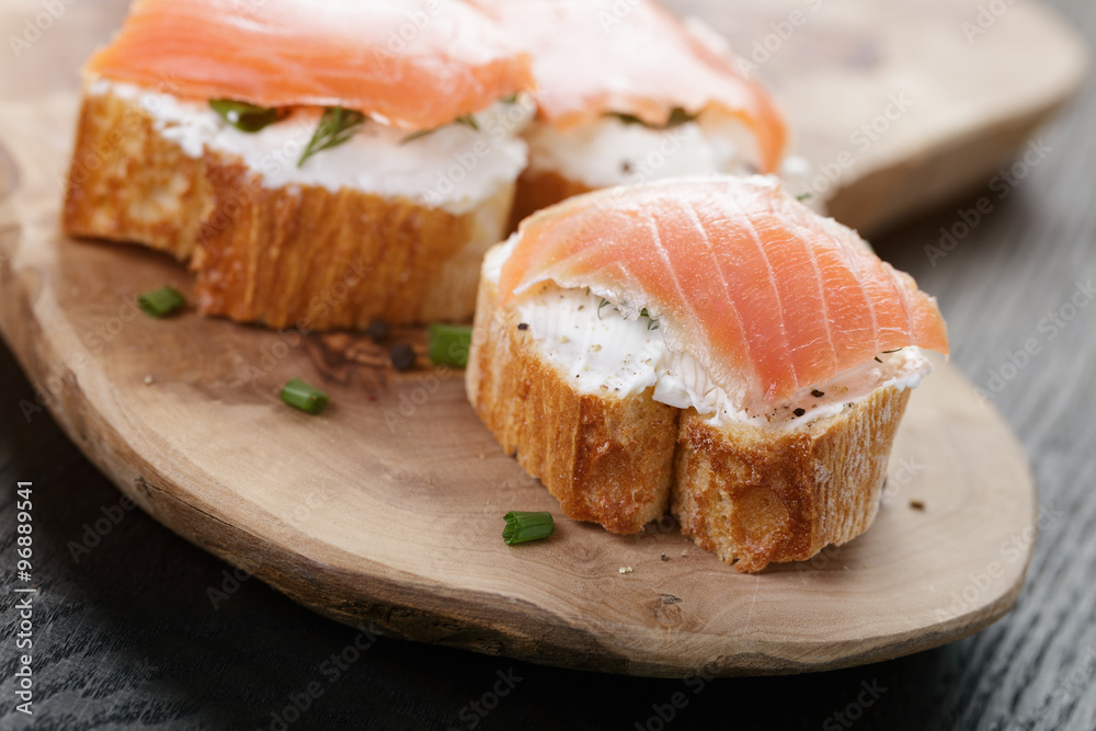 baguette slices with soft cheese and salmon on wood table baguette slices with soft cheese and salmon on wood table