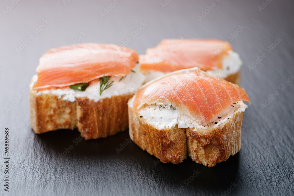 baguette slices with soft cheese and salmon on slate board