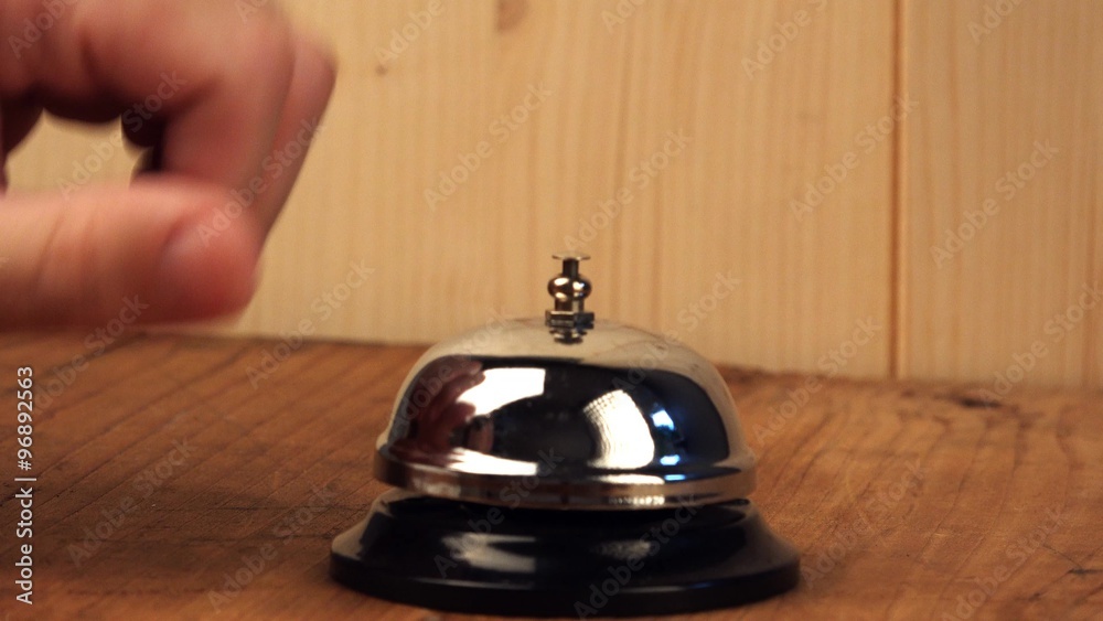 Nervous man ringing hotel reception bell, male hand pushing accommodation call bell on wooden reception front desk