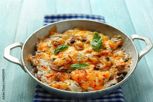 Roasted mushrooms, chicken and cheese gratin in pan, on wooden background