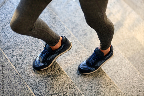 Sports woman legs in sneakers on stairs