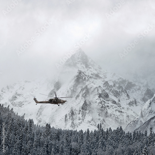 Combat helicopter over the winter mountains photo