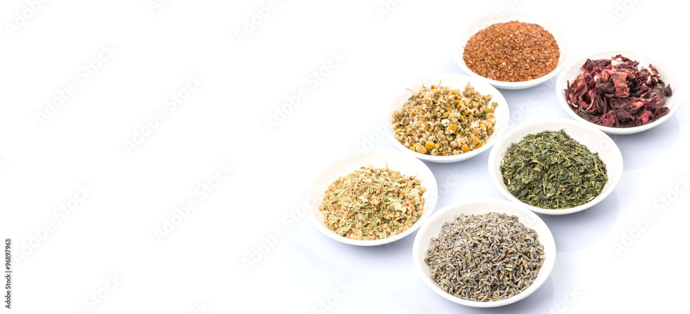 Dried herbal tea leaves, lavender, rooibos, chamomile, linden flower, hibiscus, Japanese green tea in white bowl over white background