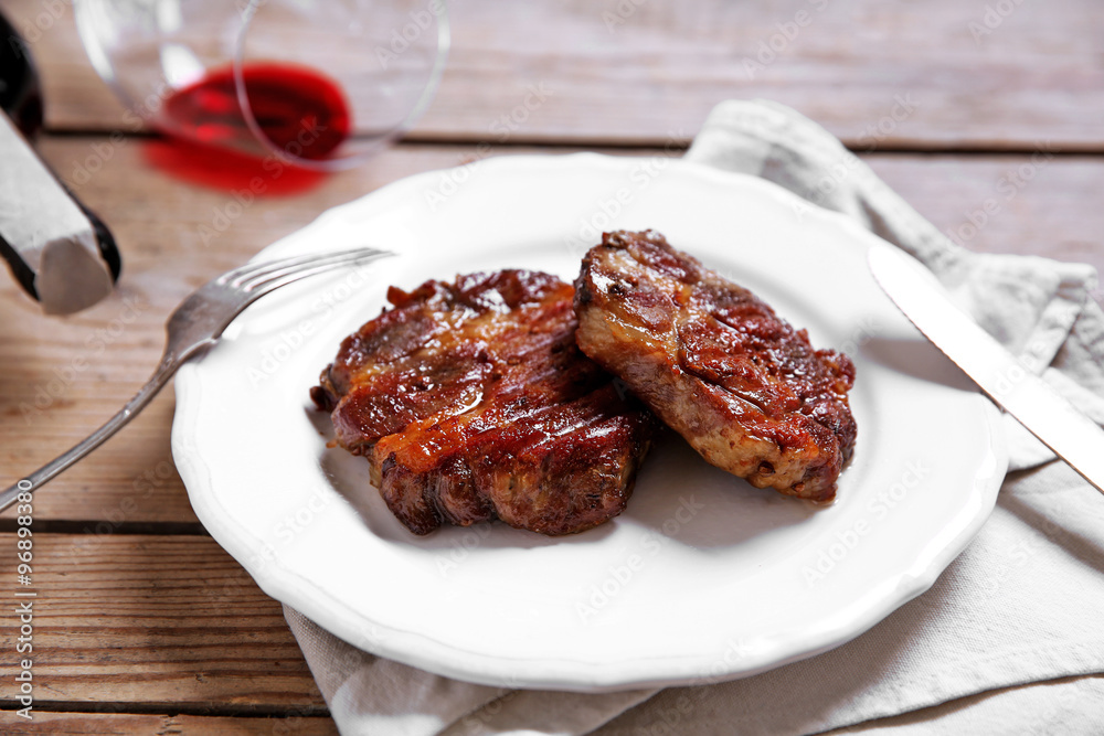 Roasted beef fillet on plate, on wooden background Roasted beef fillet on plate, on wooden background