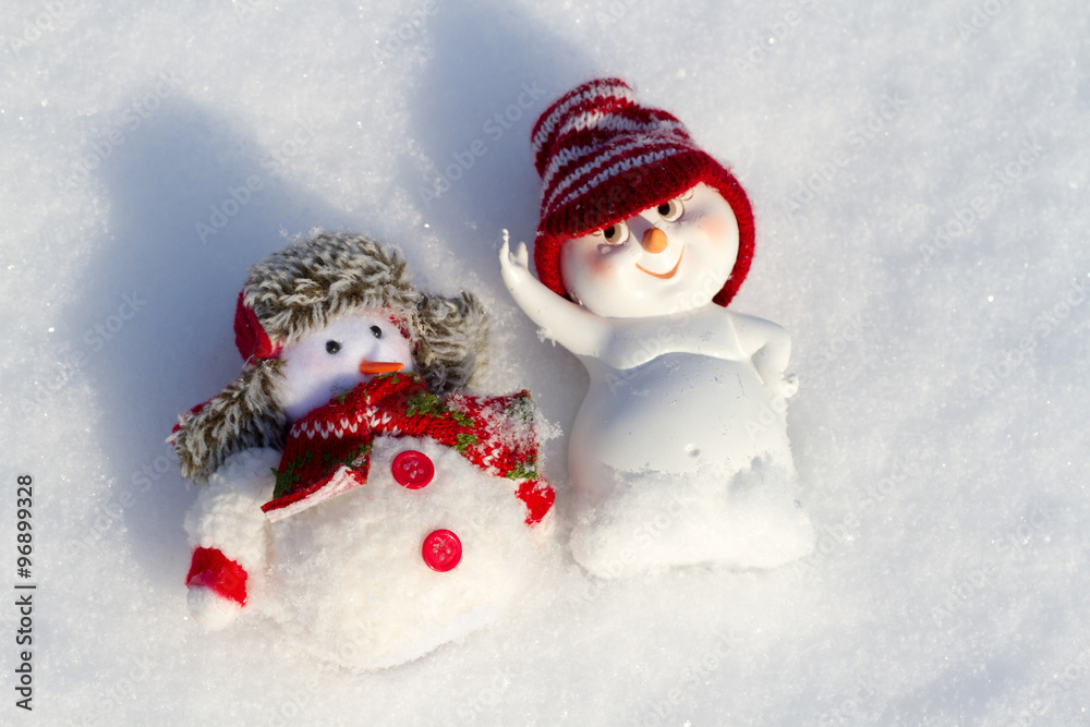 two Snowman lying on the snow
