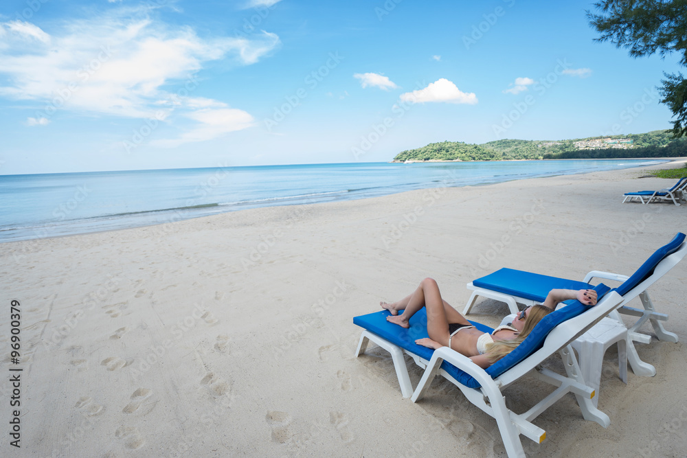 Tropical vacation. Young beautiful woman relaxing alone on the beach.