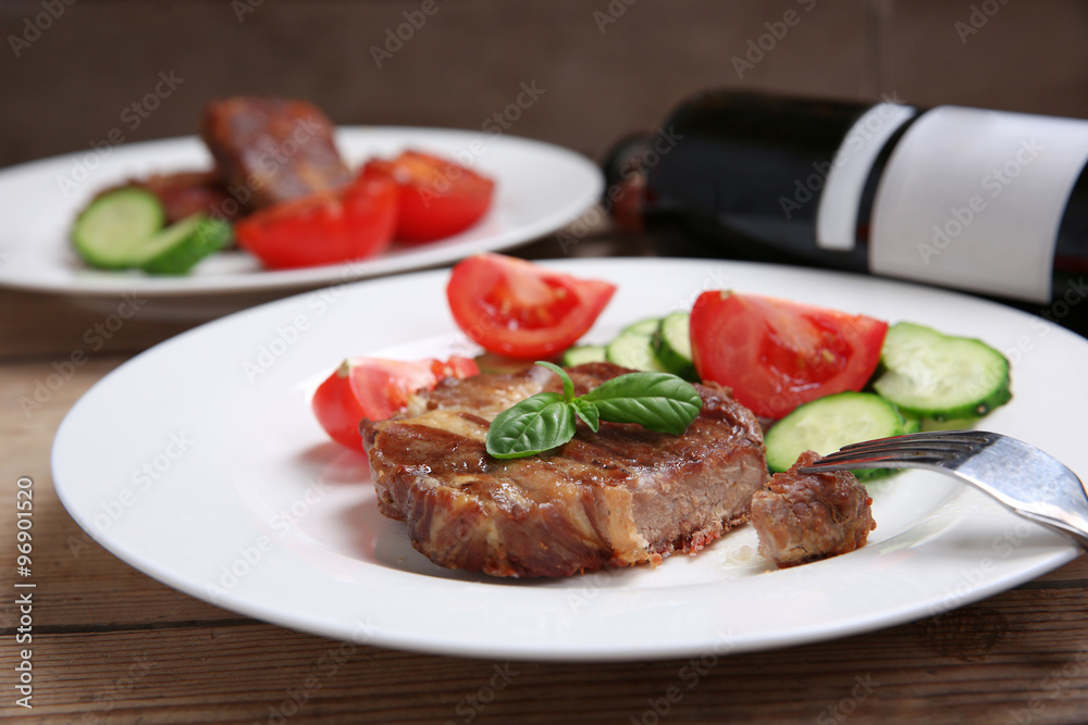 Roasted beef fillet and fresh vegetables on plate, on wooden background Roasted beef fillet and fresh vegetables on plate, on wooden background