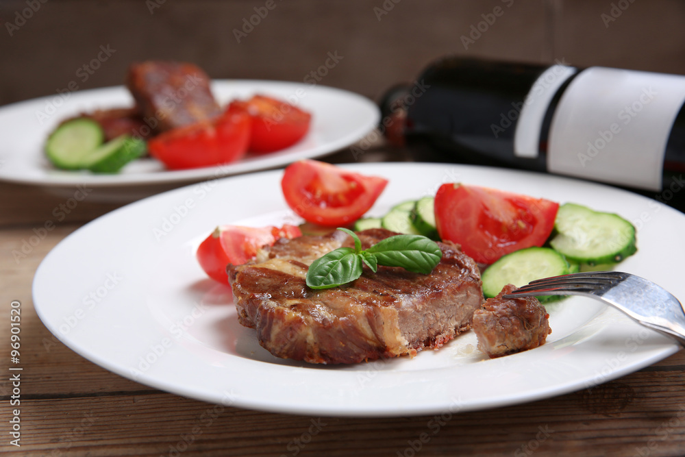 Roasted beef fillet and fresh vegetables on plate, on wooden background