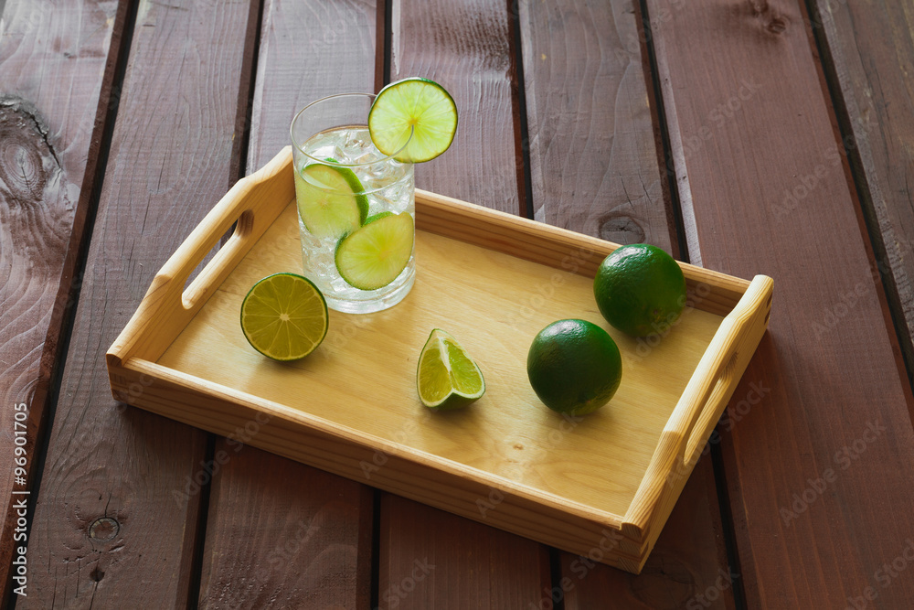 Drink on wooden tray with ice and condensation on glass