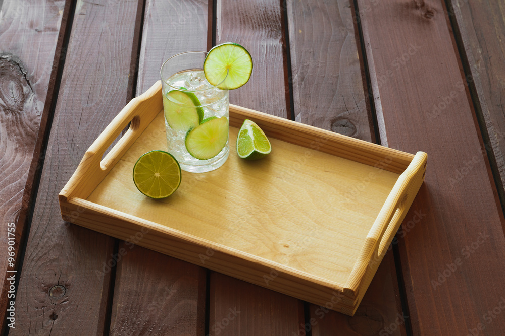 Drink on wooden tray with ice and condensation on glass