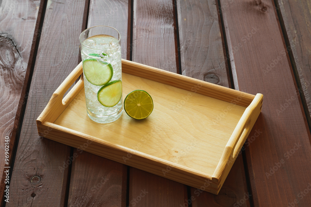 Drink on wooden tray with ice and condensation on glass