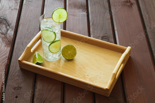 Drink on wooden tray with ice and condensation on glass