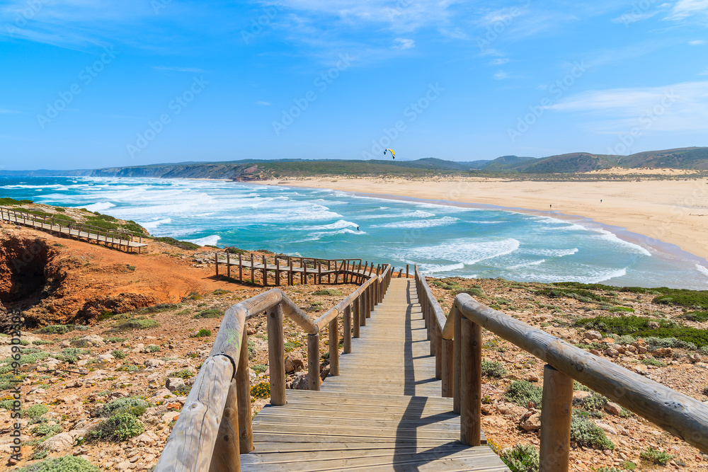 Fototapeta premium Wooden walkway to Praia do Bordeira beach and beautiful blue sea view, Algarve region, Portugal