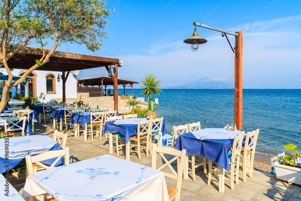 Tables with chairs in Greek tavern on sea coast, Samos island, Greece