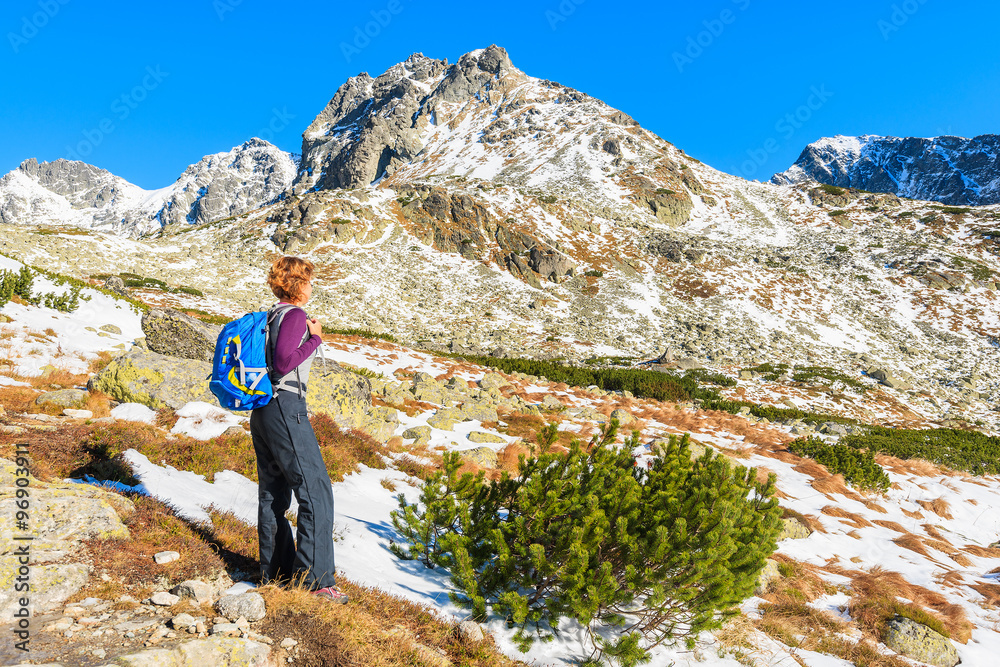 Young woman tourist looking at mountains covered with snow in autumn landscape of Hincova valley, Tatra Mountains, Slovakia Young woman tourist looking at mountains covered with snow in autumn landscape of Hincova valley, Tatra Mountains, Slovakia