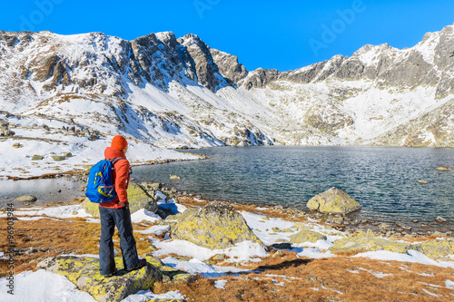 Young woman backpacker tourist standing in Hincova valley and looking at mountains covered with snow, Tatra Mountains, Slovakia