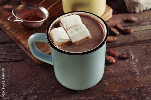 Tasty cocoa in metal old-fashioned mug and marshmallow on the table