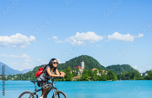 Asian tourist on a bike with beautiful scenery of lake Bled with church on island in Slovenia, Europe