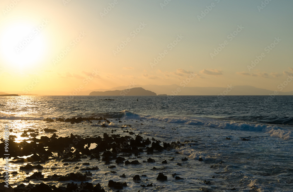 Sunset on the rocky beach in Mediterranean sea.