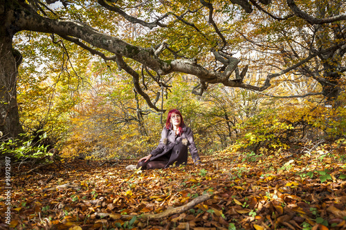 Ritratto di una ragazza dai capelli rossi seduta nella foresta