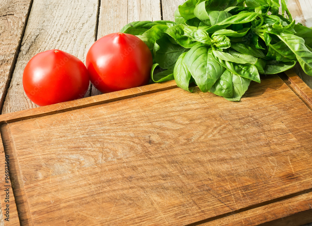 Rustic cutting board, tomatoes and basil, with copyspace Rustic cutting board, tomatoes and basil, with copyspace