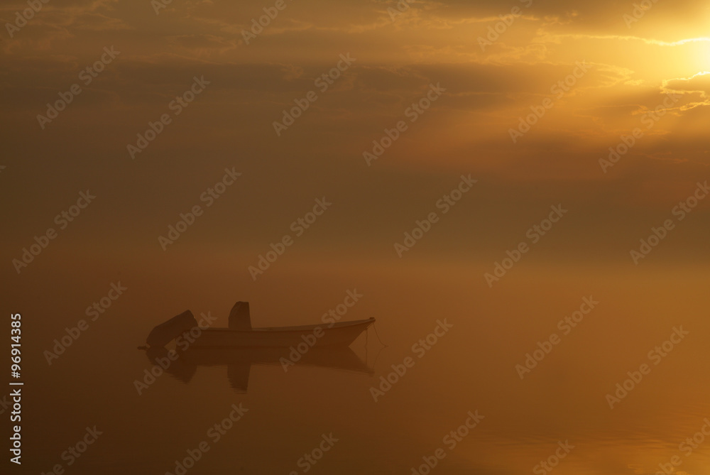 Boat in foggy sunrise