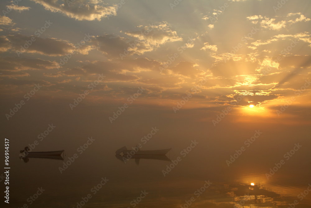 Boats in foggy sunrise