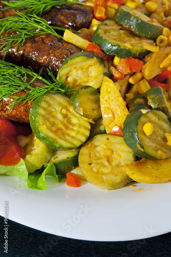 Grilled sausages with vegetables and greens on a plate